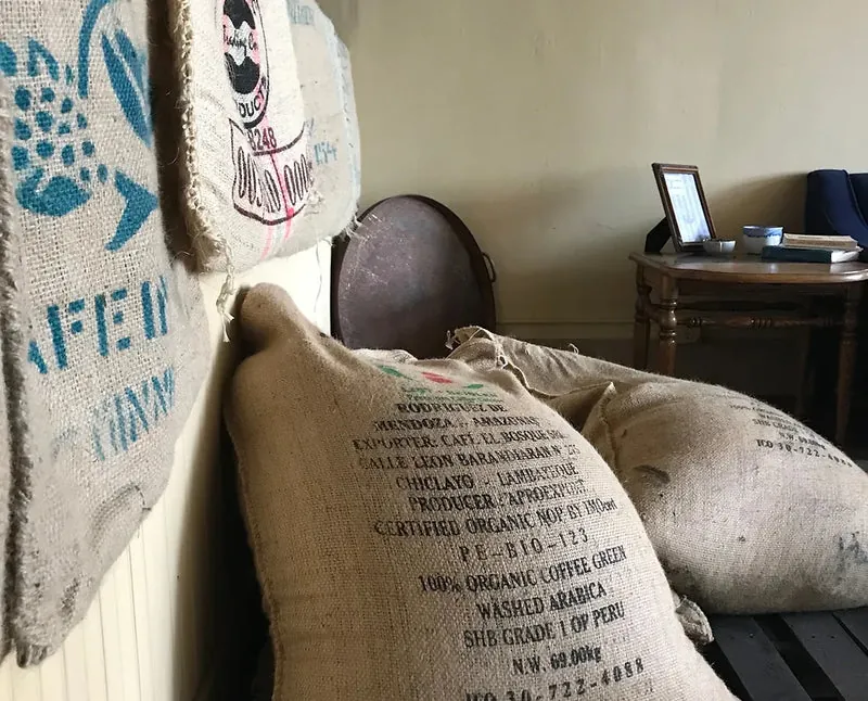 A framed burlap green-coffee sack with printed farm markings
