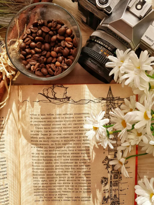 Coffee beans, a vintage camera and an open storybook on a table